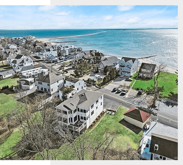 Scenic coastal town with houses overlooking the ocean under a clear sky.