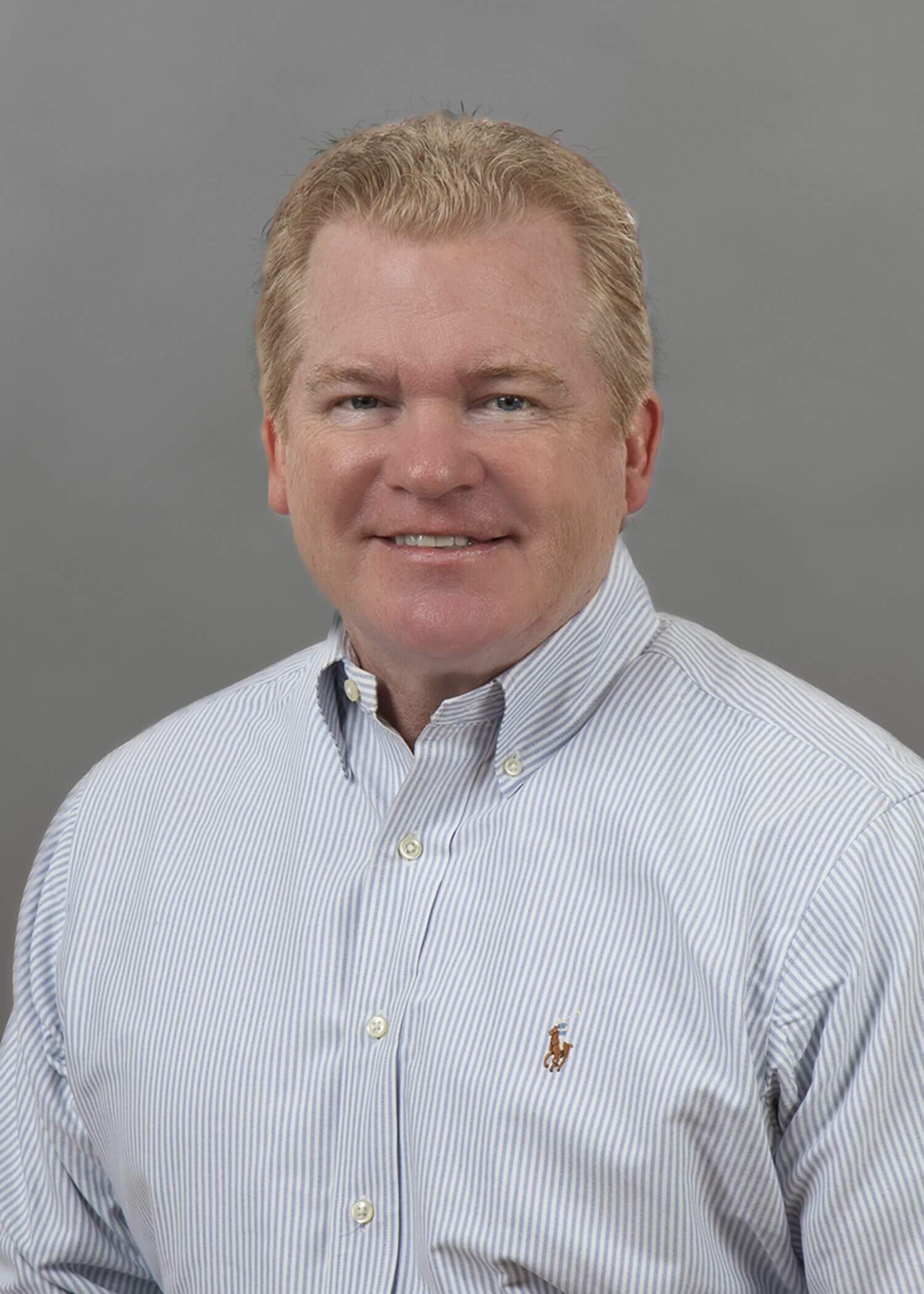 Smiling man in a striped dress shirt.